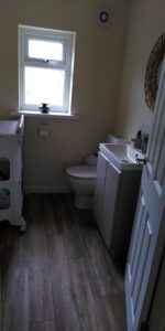 A medium sized bathroom stall with toilet, sink and baby change table